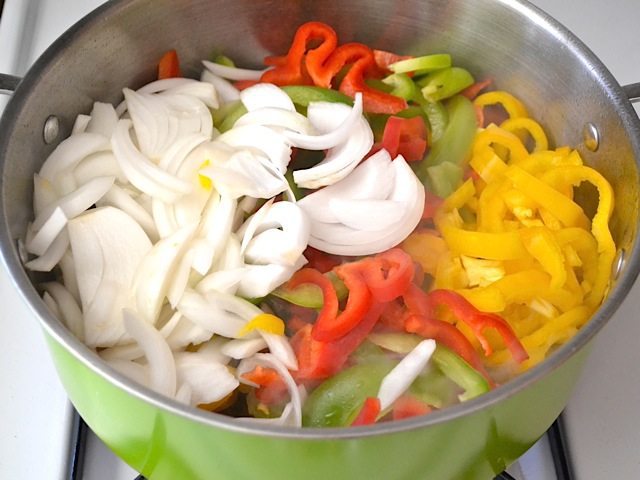 Cooking sliced peppers and onions in pot 