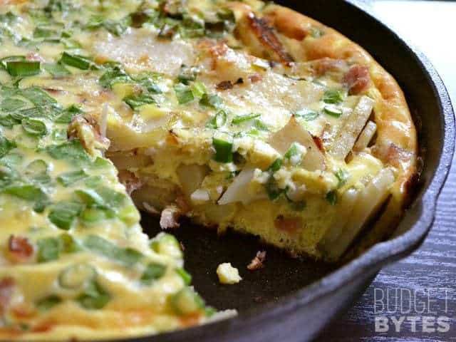 Ham and Potato Frittata in skillet with one piece taken out 