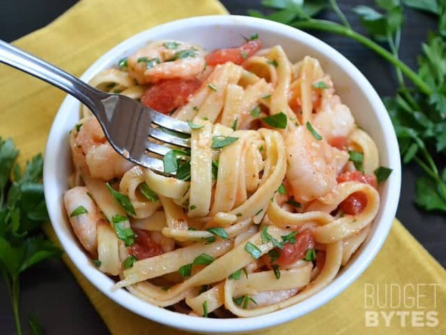 Top view of a bowl of spicy shrimp tomato pasta in bowl with fork 