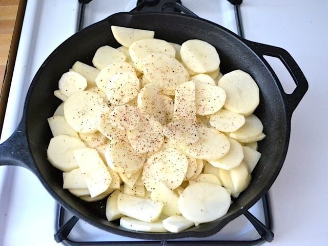 Thinly sliced potatoes and seasoning in Skillet