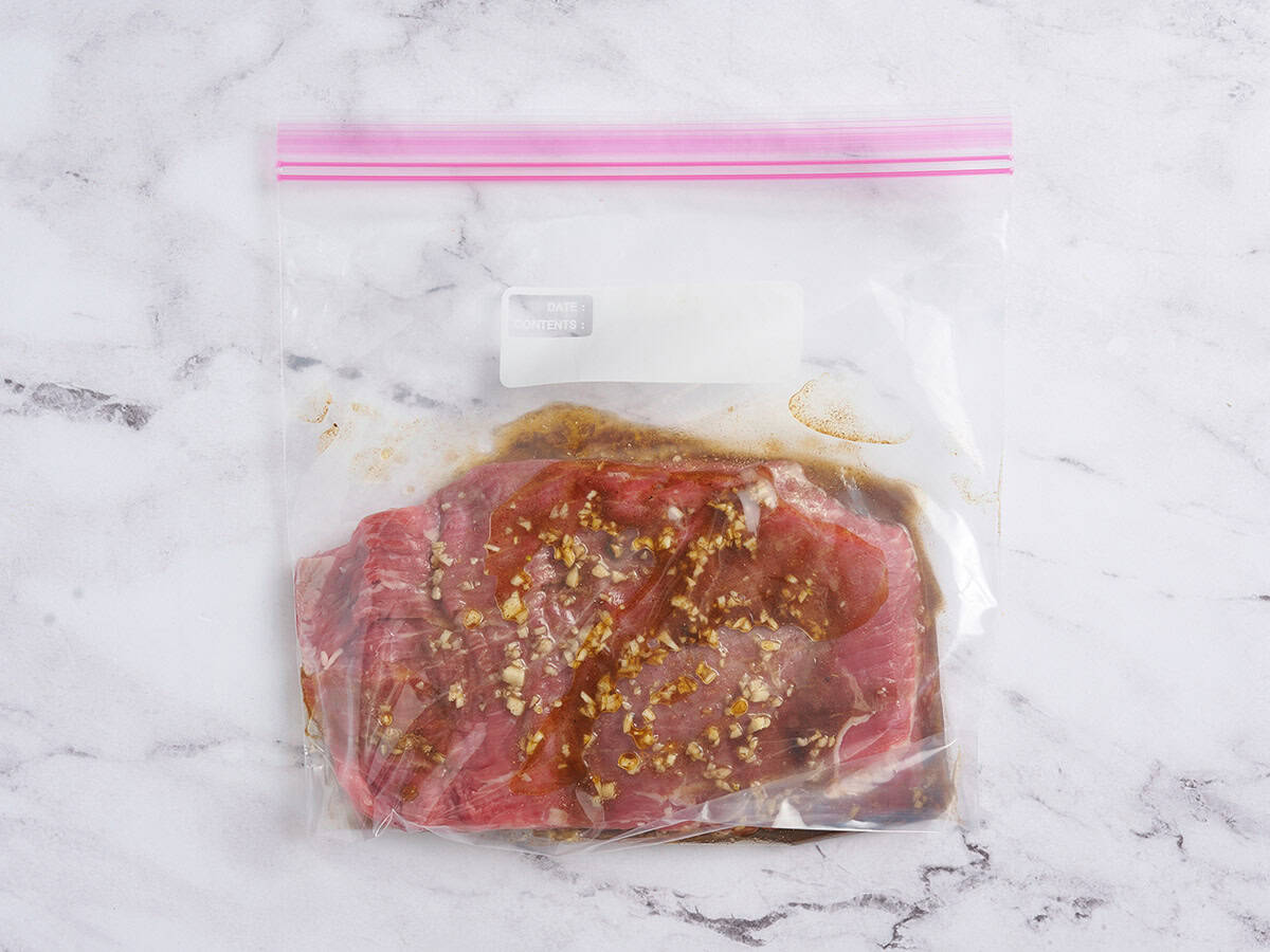 Flank steak marinating in a zip-top bag.
