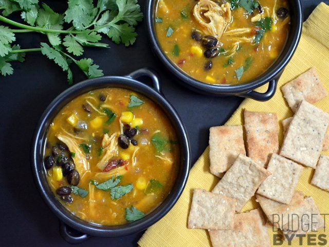 Top view of two bowls of Chicken & Pumpkin Soup with crackers on the side