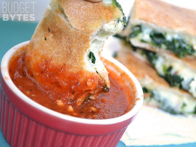 Close up of Spinach Feta Grilled Cheese being dipped in marinara sauce 