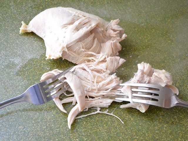 Cooked chicken removed from pot and shredded with two forks 