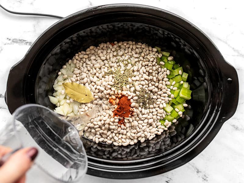 Uncooked beans, spices, herbs, and water added to the slow cooker