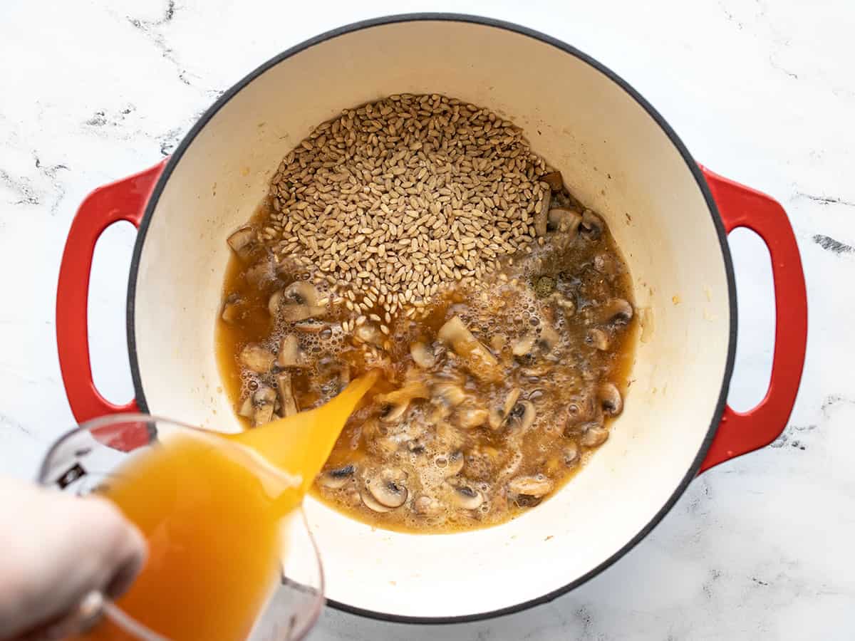 broth being poured into the pot with barley and thyme