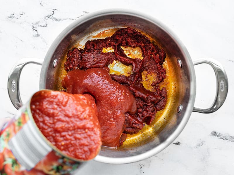 crushed tomatoes being poured into the pot