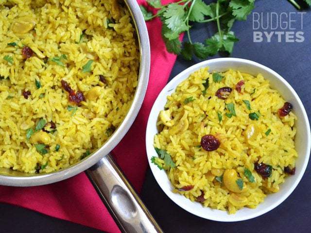 Top view of a bowl of Cashew Rice Pilaf with full skillet of dish on the side 