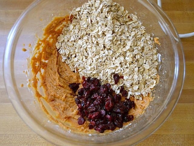 Oats and Cranberries mixed poured into mixing bowl with other ingredients 