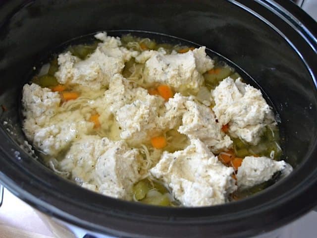 Clumps of dumpling batter dropped into slow cooker 