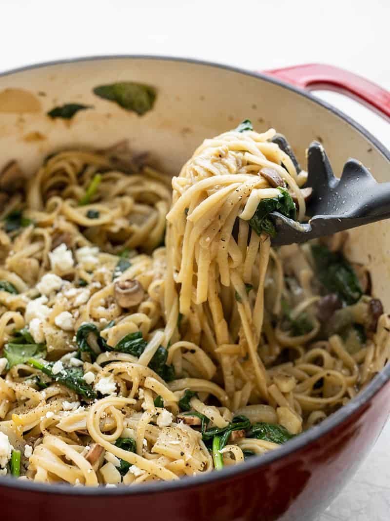 A pasta fork lifting pasta from the pot of Spinach and Artichoke Wonderpot