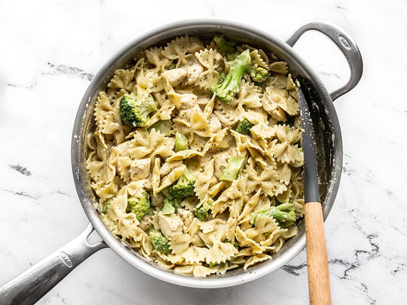 Finished creamy pesto pasta with chicken and broccoli in the skillet with a spatula