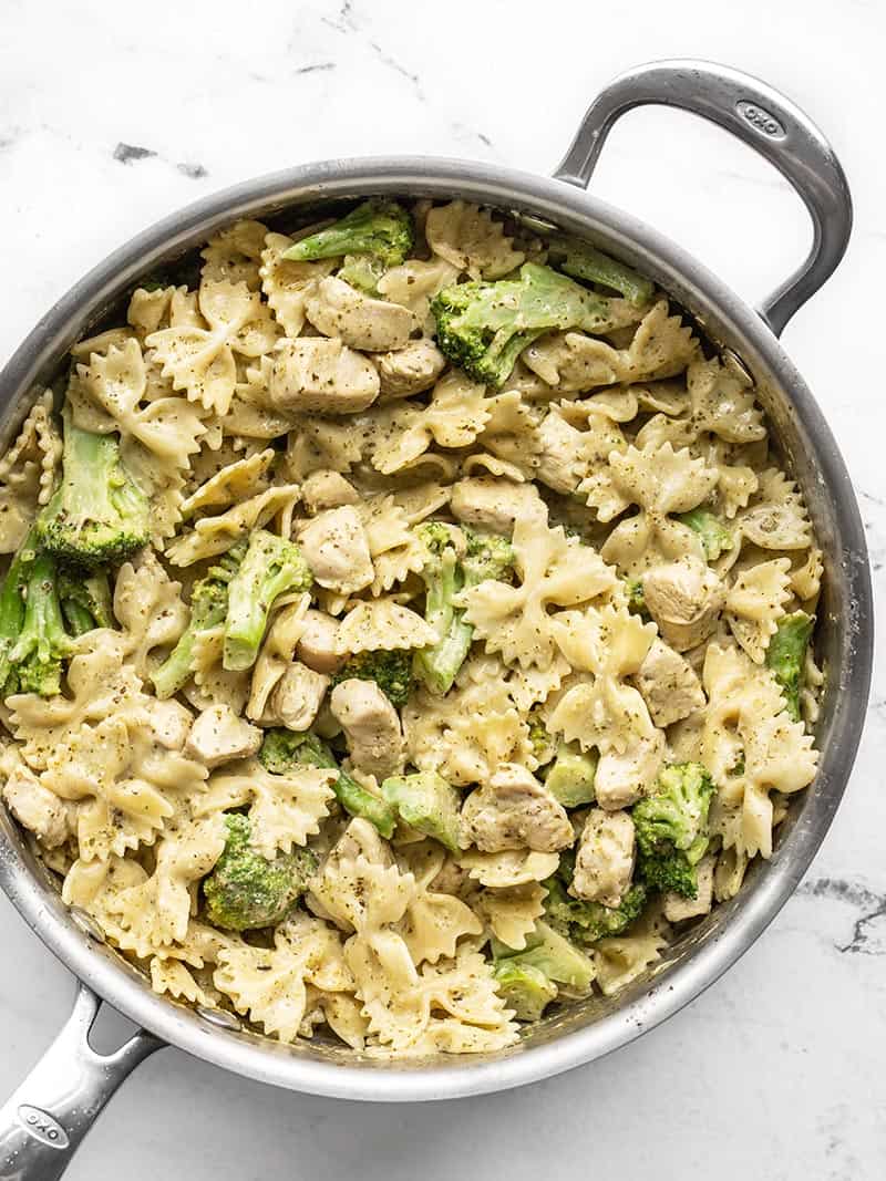 Creamy pesto pasta with chicken and broccoli in the skillet, viewed from above