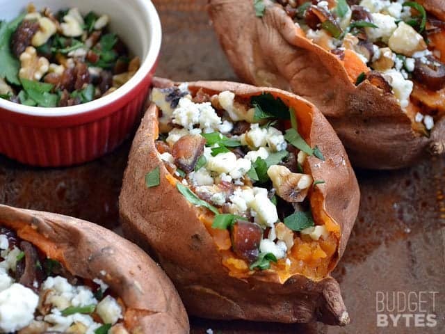 Three Date & Gorgonzola Stuffed Sweet Potatoes with a side of extra toppings in a. small bowl on the side 