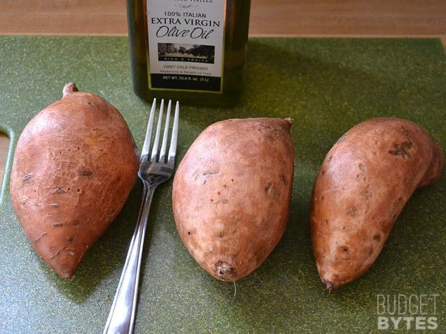 three sweet potatoes with fork to prick before cooking