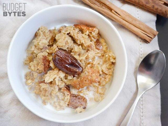 Top view of a bowl of Cinnamon Date & Walnut Oatmeal with a spoon on the side 
