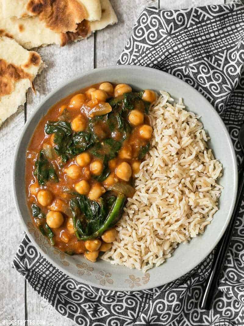 These super fast Curried Chickpeas with spinach are packed with flavor and nutrients, vegan, gluten-free, and filling! Plus they freeze great! A bowl full of Curried Chickpeas with Spinach and brown basmati rice.