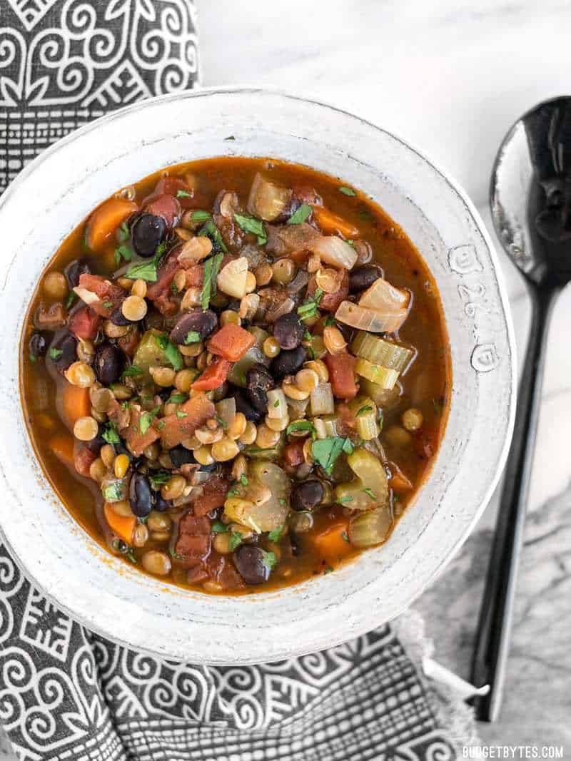 Top view of a bowl of Chunky Lentil and Vegetable Soup with a spoon on the side 