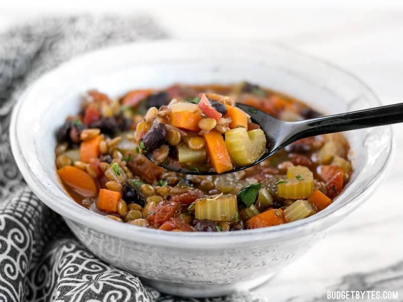 Side view of a bowl of Chunky Lentil and Vegetable Sop with spoon 