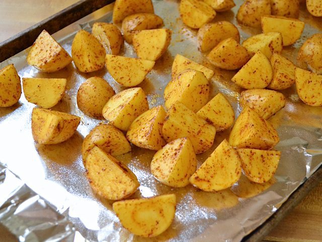 seasoned potatoes placed on baking sheet