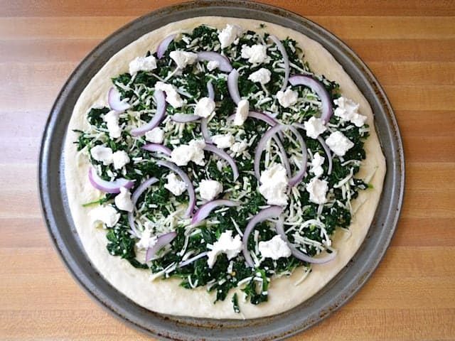Pizza toppings added to crust, spinach mixture, red onion and goat cheese 