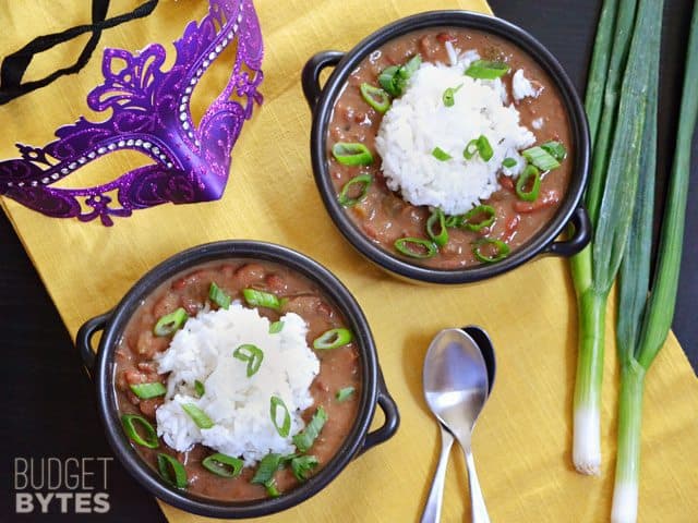Top view of two bowls of Vegan Red Beans and Rice, with spoons and green onions on the side 