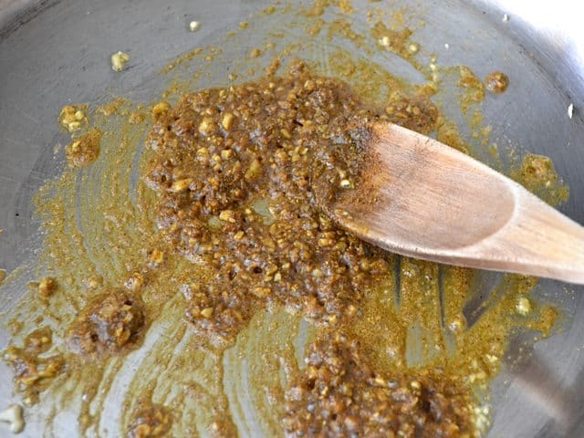 Curry Powder added to garlic and onion in skillet, mixed with wooden spoon 