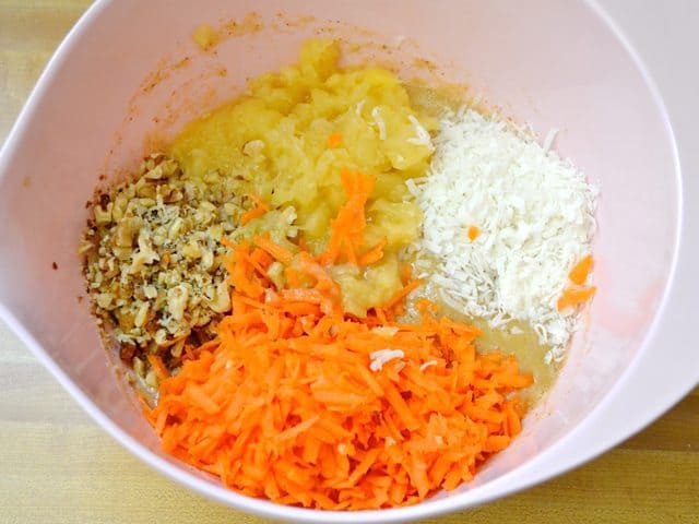 Pineapple, carrots and nuts added to wet ingredients in mixing bowl 