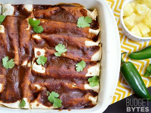 Beef & Pineapple Enchiladas garnished with cilantro, pineapple and jalapeños on the side 