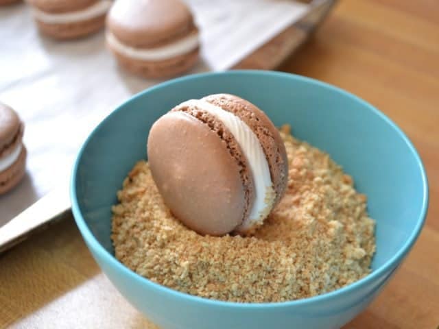 Dipping finished macarons in crushed graham crackers 