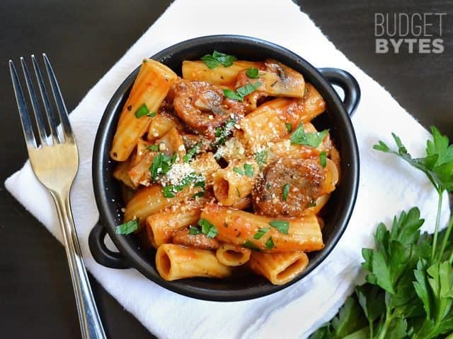 Top view of a bowl of One Pot Sausage & Mushroom Pasta with napkin and fork 