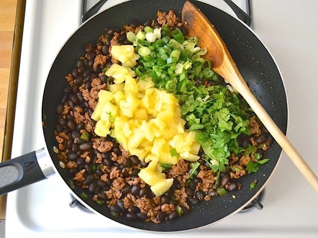 Pineapple and cilantro added to skillet with other ingredients 