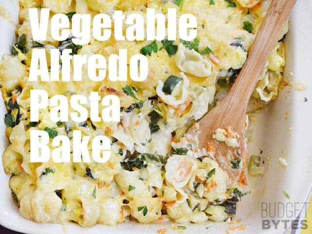 Top view of a pan of Veggie Alfredo Pasta Bake with wooden spoon 