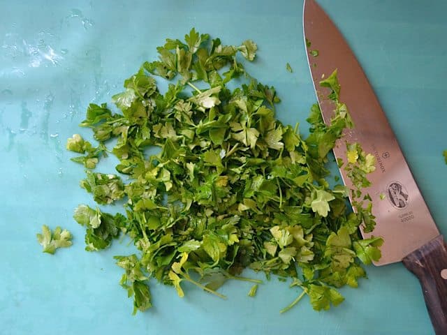 Chopped cilantro and parsley leaves with knife 