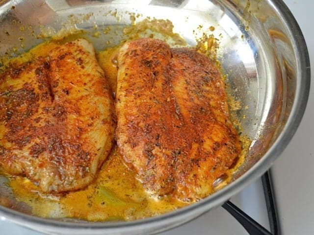 Cooked Tilapia in skillet on stove top 