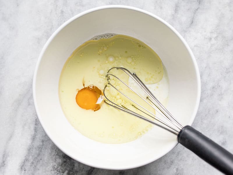 Lemon Blueberry Cornbread wet ingredients in a bowl with a whisk