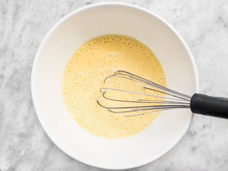 Milk and Eggs whisked with whisk in mixing bowl 