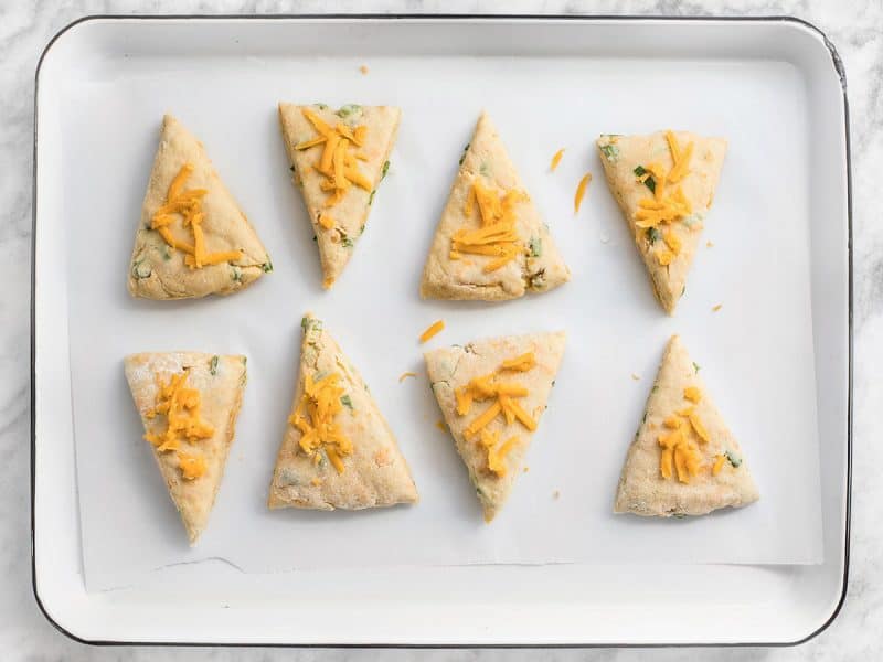 Cheddar Scallion Scones with cheddar cheese sprinkled on top, ready to bake 