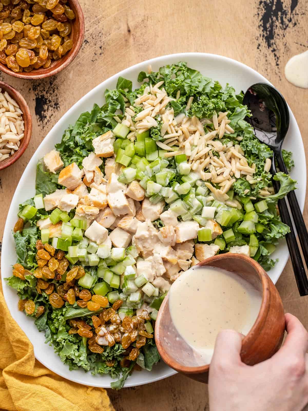 Dressing being poured over a kale and chicken salad