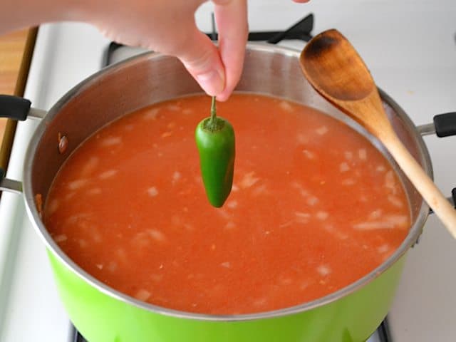 Jalapeño being dropped into pot with all other ingredients 