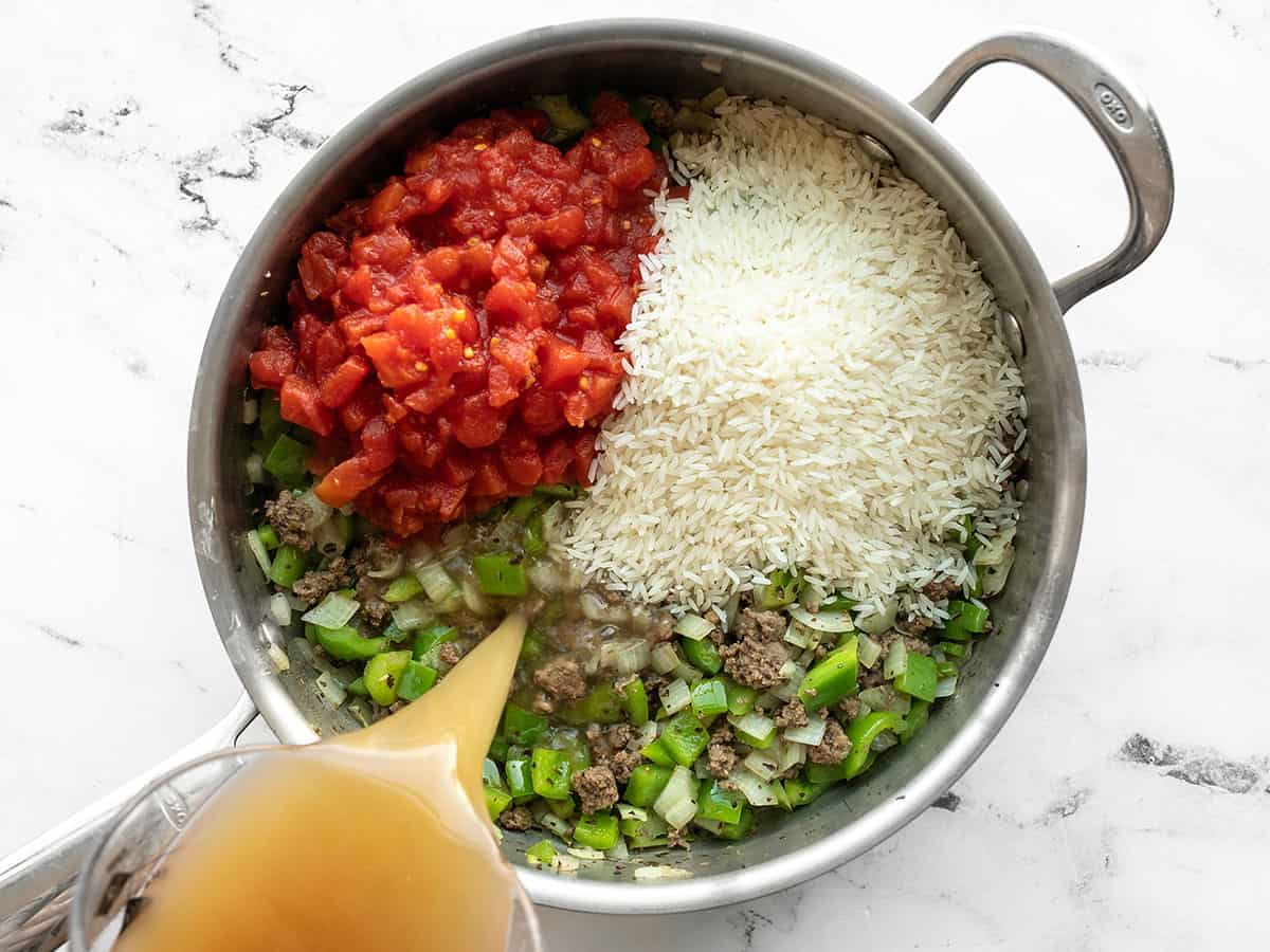 Tomatoes, rice, and broth added to the skillet.