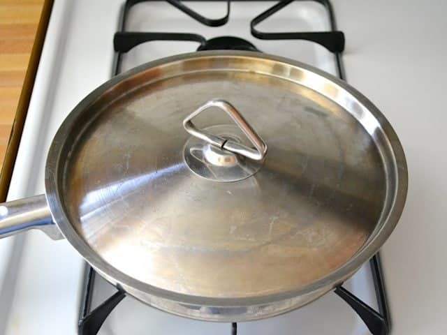 Lid placed on skillet, mixture simmering 
