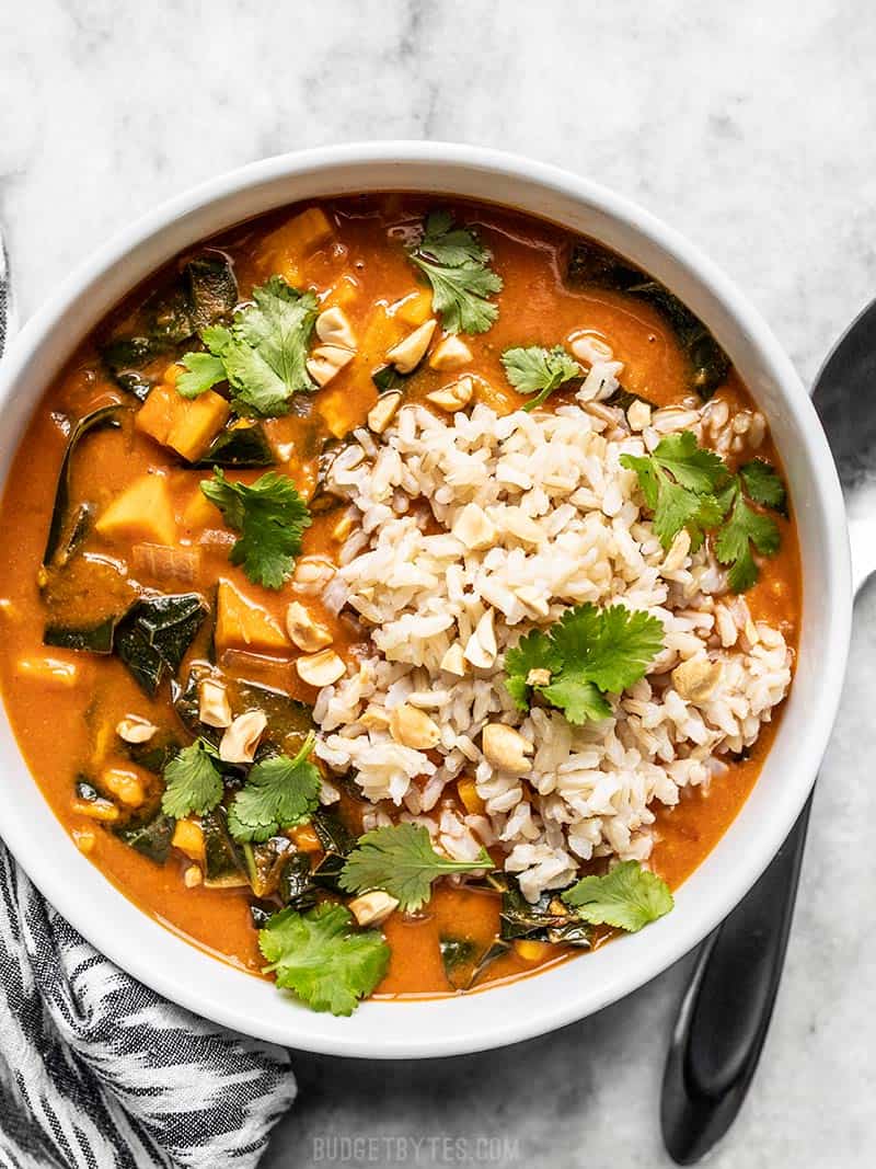 A white bowl of Vegan West African Peanut Stew with brown rice and cilantro.
