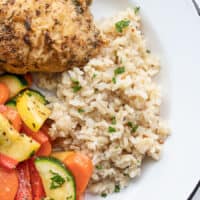 Seasoned rice on a plate with vegetables and chicken