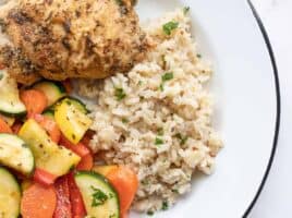 Seasoned rice on a plate with vegetables and chicken