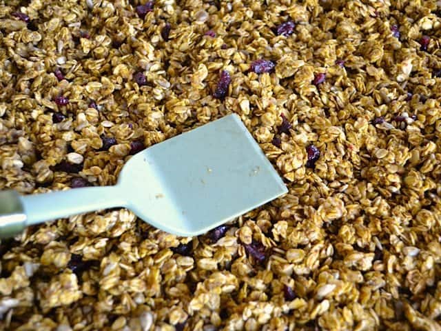 Chopped cranberries added to baked granola and mixed in, mixture pressed back down on baking sheet with spatula 