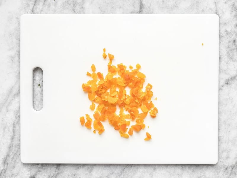 Chopped dried apricots on a white cutting board