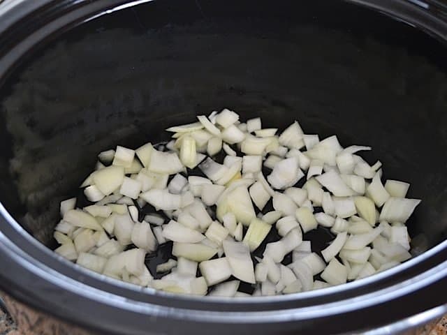 Diced onion and wine in bottom of slow cooker 
