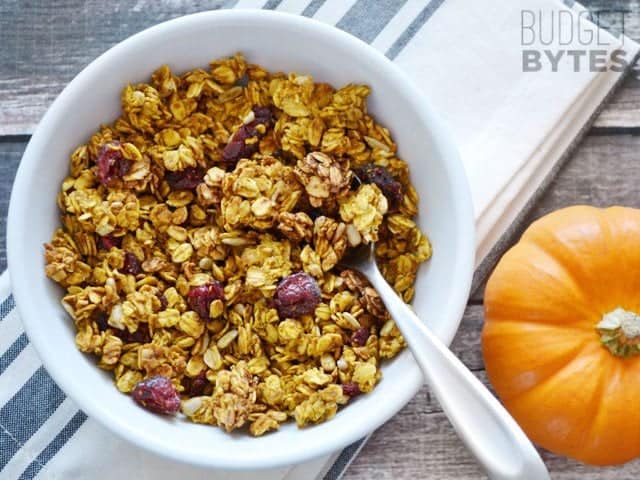 Top view of a bowl of Pumpkin Spice Granola with a little pumpkin on the side 