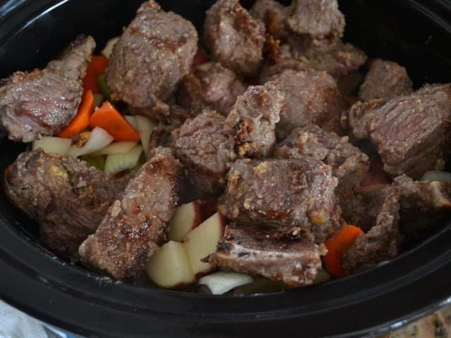 Stew meat and seasoned broth added to slow cooker with the chopped vegetables